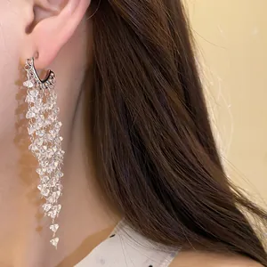Detailed close-up showing elegant silver tassel drop earrings with sparkling crystals on model