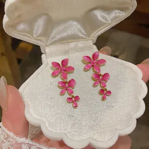 Detailed view of pink enamel flower tassel earrings presented in a white shell gift box