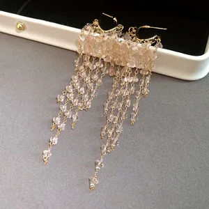 Detail view of pink crystal tassel earrings draped over a luxury jewelry box