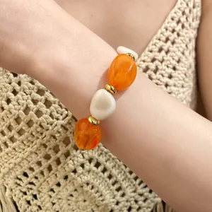 Detail view of vintage acrylic oval beaded bracelet with orange and cream beads