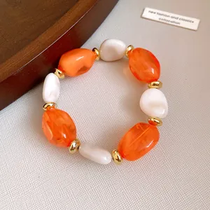 Detailed view of an elegant acrylic geometric oval beaded bracelet in orange and white