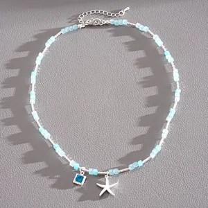 Détail d'un collier en perles de verre bleu clair avec étoile de mer et pierre carrée argentée
