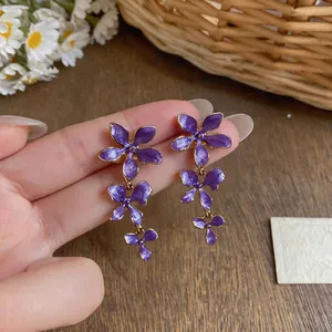 Detail view of purple enamel flower tassel earrings with elegant golden metallic edges
