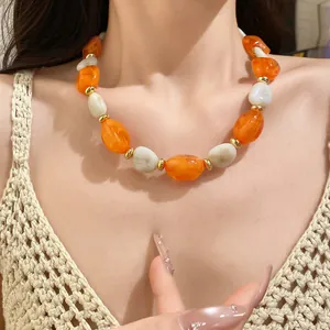 Detail shot of vintage acrylic oval beaded necklace with orange and marble-white beads.