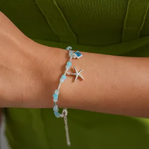 Détail d'un bracelet à perles bleues avec breloques étoile de mer et pierre précieuse