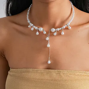 Detailed view of elegant white pearl necklace with teardrop tassel worn by model.