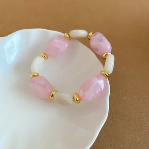 Elegantes Armband mit rosa und weißen Acrylperlen sowie stilvollen goldenen Zwischenperlen