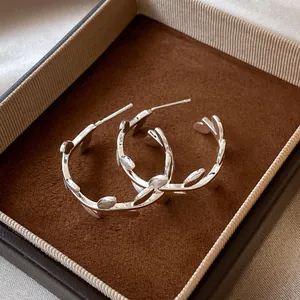 Gros plan de boucles d'oreilles créoles en argent en forme de feuille dans un coffret