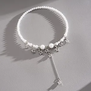 Close-up of pearl choker necklace featuring silver star charms and tassel drop.