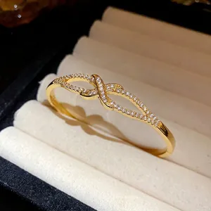 Bracelet jonc plaqué or 18 carats avec motif nœud en zircons dans un écrin à bijoux
