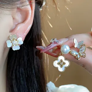 Gros plan de boucles d'oreilles plaquées or 14 carats avec détails fleurs et papillons.