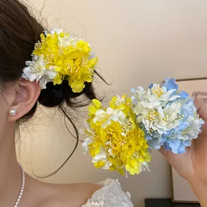 Close-up of yellow and blue fabric floral hair clips being worn on hair and held
