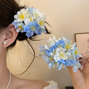 Close-up detail of a blue and white fabric floral hair clip accessory worn on elegant side hair