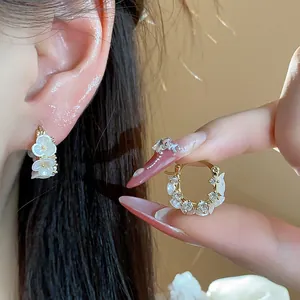 Gros plan sur d'élégantes boucles d'oreilles fleurs et papillons en plaqué or 14k