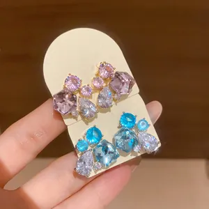 Detail view of sparkling geometric zircon waterdrop stud earrings in pink and blue.