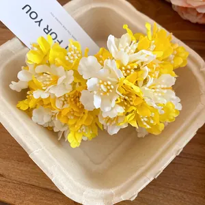 Detailed view of yellow and white fabric flower hair clips in a natural setting