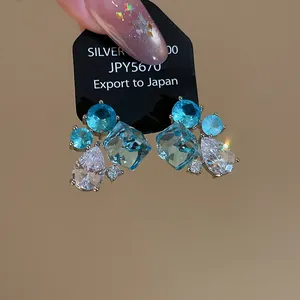 Macro view of blue and clear geometric cubic zirconia stud earrings on black card