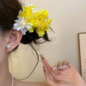 Detail view of a fabric flower hair clip in yellow and white worn on a female model.