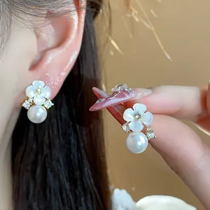 Détail de boucles d'oreilles perles fleurs plaquées or 14 carats et accents zircon.