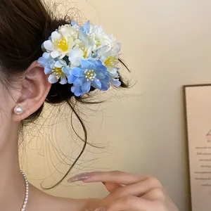 Detailed view of a sweet light blue and white fabric flower hair clip worn on a side bun.