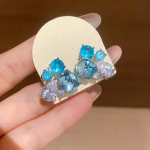 Close-up of blue and clear geometric zircon teardrop stud earrings on a display card.