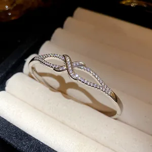 Détail d'un jonc ovale plaqué or 18 carats avec un design de nœud serti de zircons
