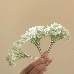 Detailed view of three green flower U-shaped hairpins held in hand for Hanfu styling