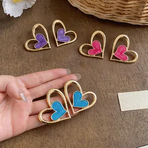 Vista detallada de los pendientes de corazón de esmalte con marco dorado calado.