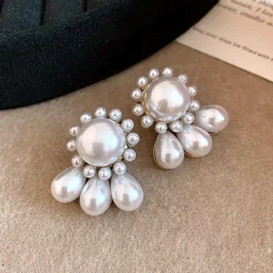 Close-up detail of retro French style stud earrings with round and teardrop pearls.