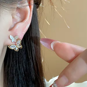 Gros plan d'élégantes boucles d'oreilles papillon plaquées or 14k avec zircons