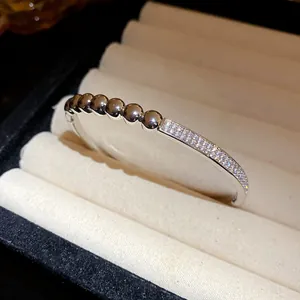 Gros plan détaillé d'un jonc ovale argenté avec des billes lisses et un pavé de zircons