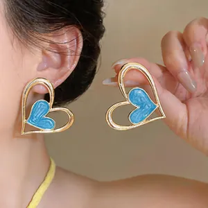Vista detallada de elegantes pendientes de corazón en esmalte azul en el lóbulo