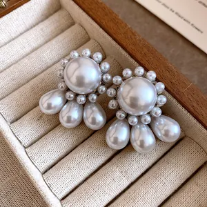 Close-up of French vintage palace style earrings with round and teardrop pearls.