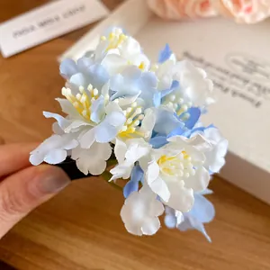 Detailed macro shot of a sweet blue and white fabric floral duckbill hair clip accessory.
