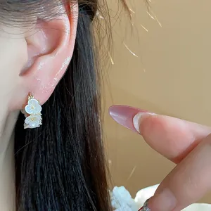 Élégantes boucles d'oreilles fleurs plaquées or 14 carats avec pétales blancs sur l'oreille