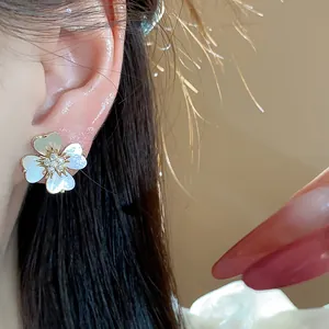 Détail d'une boucle d'oreille fleur minimaliste plaquée or 14 carats avec zircons sur l'oreille