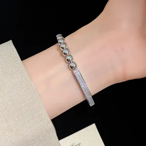 Bracelet élégant plaqué or 18 carats avec barre de zircons et perles au poignet.