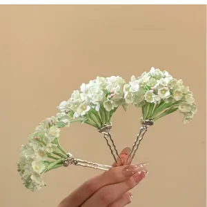 Hand-held detail of elegant green floral U-shaped hairpins for traditional Hanfu style.