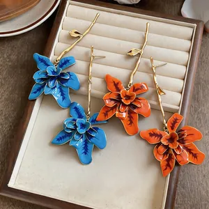 Detailed view of elegant long flower dangle earrings in blue and orange enamel finish