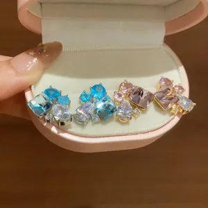Close-up of elegant geometric and teardrop zirconia earrings in blue and pink tones