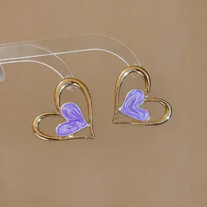 Primer plano de aretes de corazón con efecto de aceite goteado púrpura y acabado oro