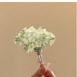 Macro detail of elegant U-shaped hair fork featuring delicate white and pink flowers