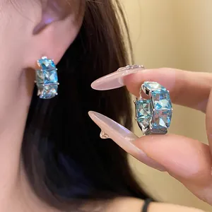 Dettaglio di orecchini a cerchio vintage con zirconi blu indossati