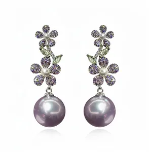 Détail de boucles d'oreilles pendantes fleurs avec zircon violet et perles