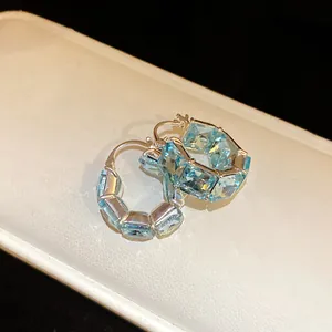 Primo piano di orecchini a cerchio vintage con zirconi blu a taglio quadrato in argento.