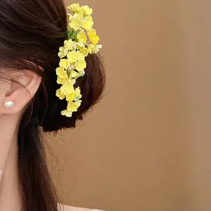 Detailed side view of a delicate yellow floral hairpin worn on a dark hair bun