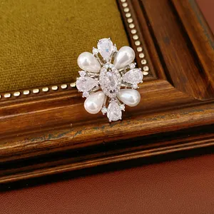 Dettaglio di un anello a forma di fiore con perle lucenti e pietre di zirconia cubica.