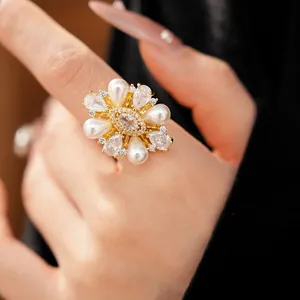 Vista dettagliata di un anello a fiore placcato oro con perle e zirconi brillanti sul dito.
