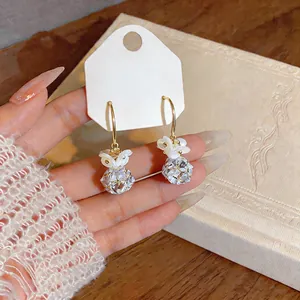 Detailed view of French-style gold hoop earrings with white zircon flower pendant charm