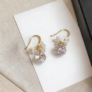 Macro view of French style gold ear hooks with pearl flowers and faceted zircon drop ball